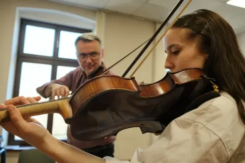 lekcja skrzypiec, na pierwszym planie studentka trzymająca instrument, na drugim planie profesor również z instrumentem.