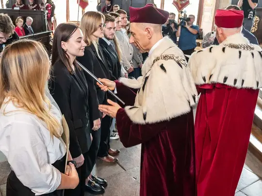Immatrykulacja student&oacute;w pierwszego roku. Przewodniczący KRUWiO prof. dr hab. Krystian Kiełb berłem dokonuje uroczystego aktu pasowania, JM Rektor UE prof. dr hab. Andrzej Kaleta wręcza teksty roty