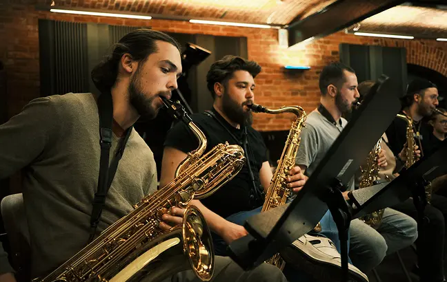 Zdjęcie przedstawia czterech mężczyzn grających na instrumentach