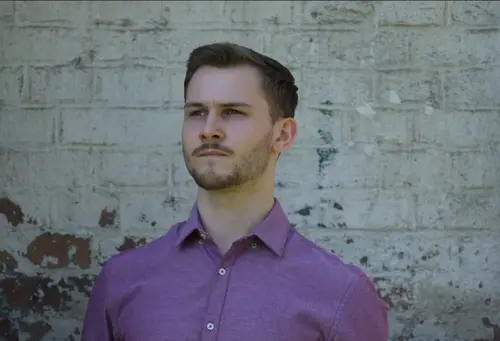 Jakub Kołodziejczyk stoi na tle muru